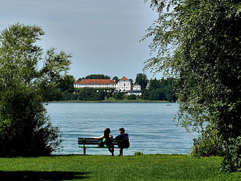 Couple sitting on bench overlooking lake with castle in distance