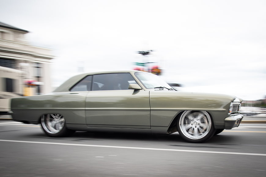 Vintage olive green classic car driving on city street