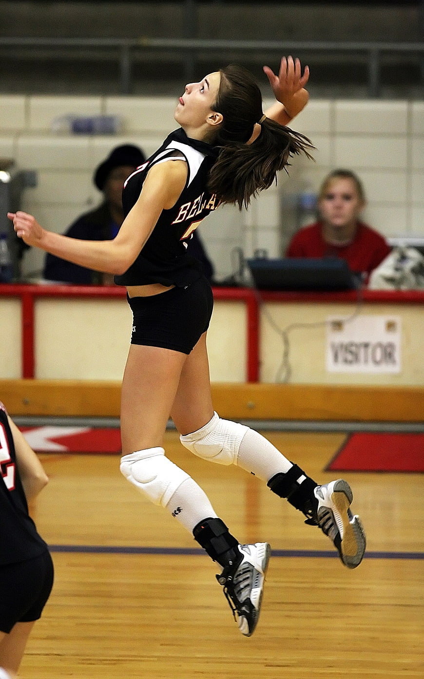 Female volleyball player jumping to spike the ball in an indoor gymnasium