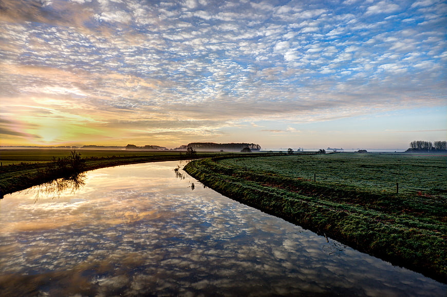 Serene River Landscape at Sunrise with Cloud Reflections