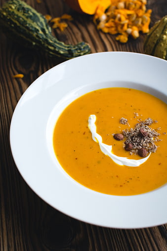 Creamy Pumpkin Soup with Cream and Nuts on Wooden Table