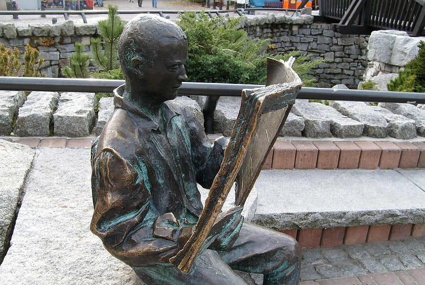 Bronze statue of a boy reading a large book