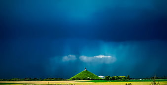 Dramatic Green Hill Under Dark Blue Storm Sky