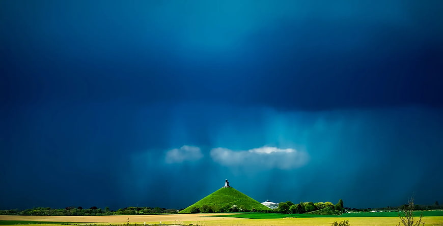 Dramatic Green Hill Under Dark Blue Storm Sky