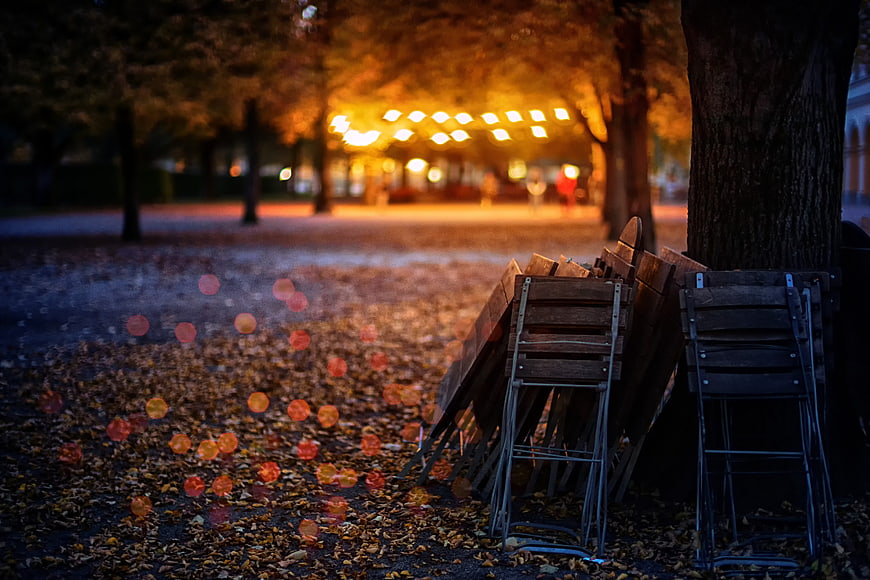 Folded Garden Chairs And Autumn Leaves In A Park At Night