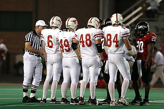 Football players and referee huddle on field