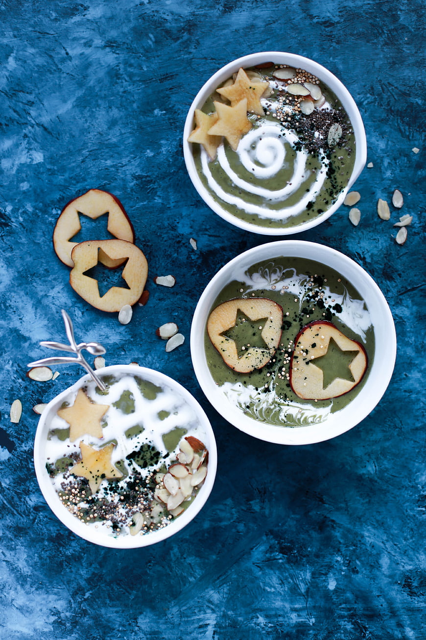 Overhead view of green smoothie bowls with star-shaped apple slices