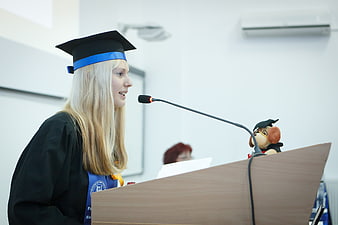 Female graduate giving speech at podium with stuffed animal