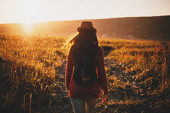 Woman Walking on Trail in Golden Hour Field