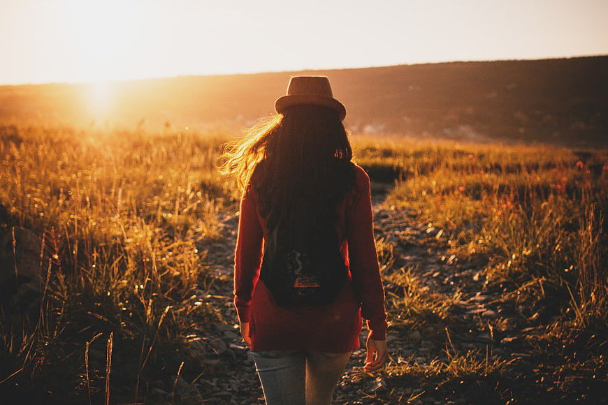 Woman Walking on Trail in Golden Hour Field