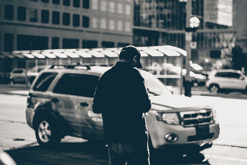 Man in Cap Standing by Car on City Street