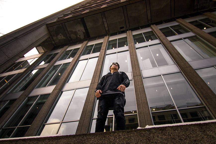 Low angle shot of young man standing in front of modern building