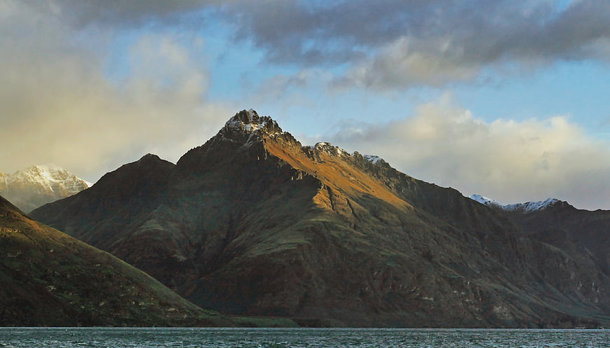 Sunlit Mountain Peak Over Lake with Cloudy Sky