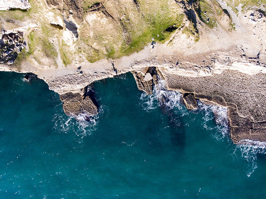 Aerial view of rugged coastline with turquoise ocean waves