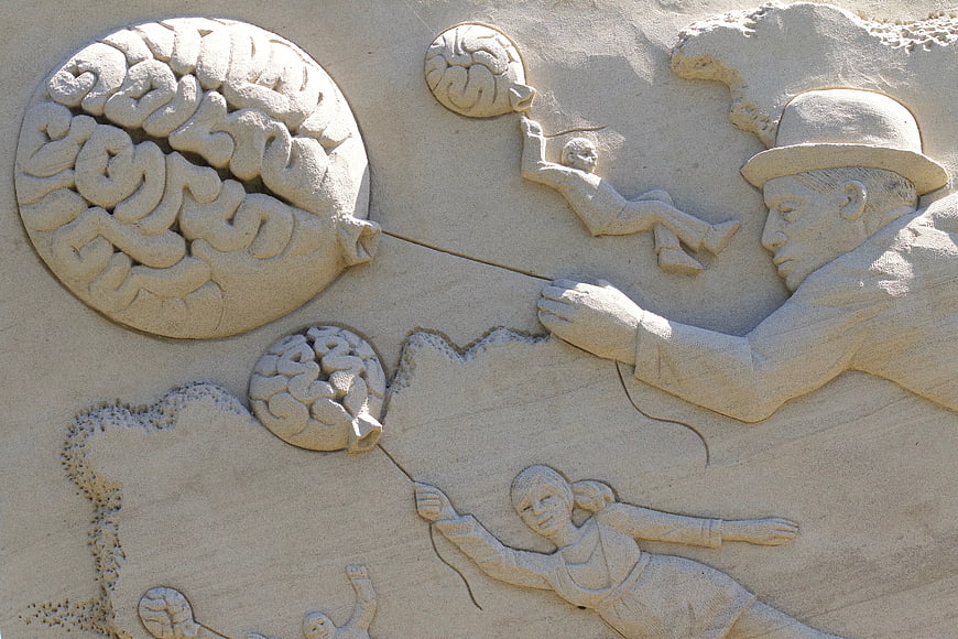 Detailed sand sculpture of brain-shaped balloons and floating figures