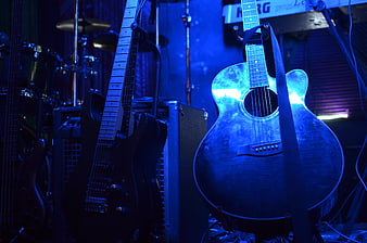 Electric and acoustic guitars on stage with blue concert lighting