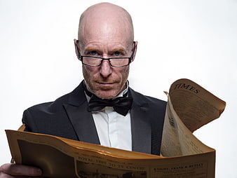 Bald man in tuxedo reading vintage newspaper