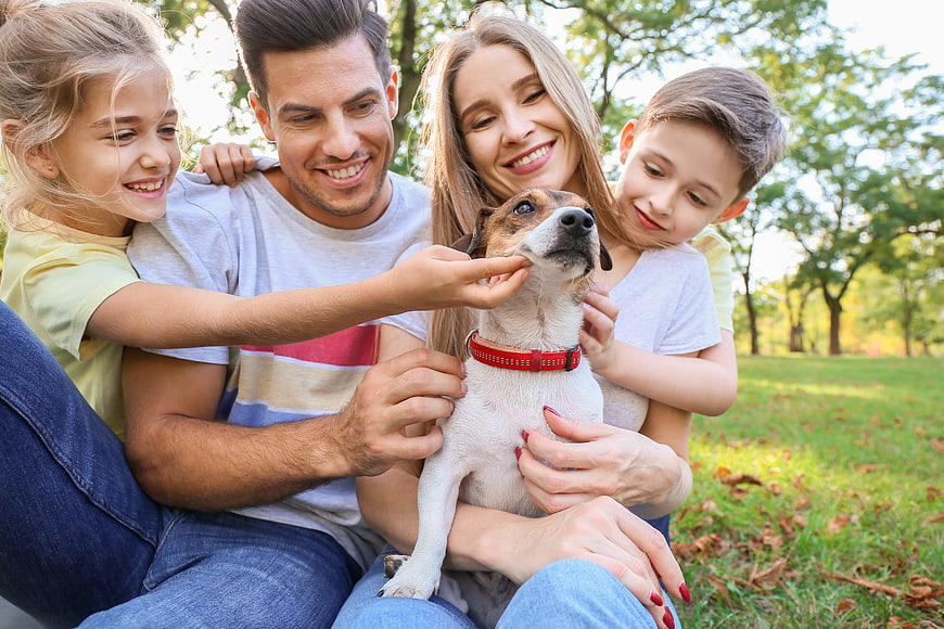 Happy family with dog sitting in park