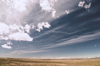 Vast open landscape with dramatic clouds and distant mountains