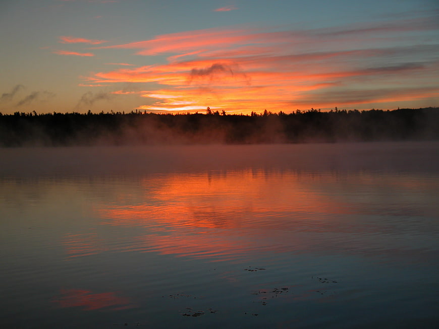 Misty Sunrise Over Lake with Vibrant Orange Sky Reflection