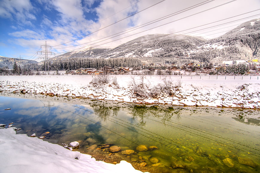Snowy River with Mountain Village Reflection in Winter
