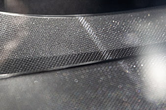 Close-up of textured metallic mesh with bokeh highlights
