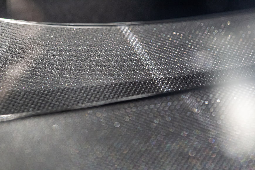 Close-up of textured metallic mesh with bokeh highlights