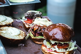 Gourmet burgers being prepared on a wooden board