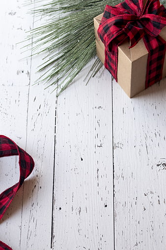 Christmas gift box with plaid ribbon on white wood