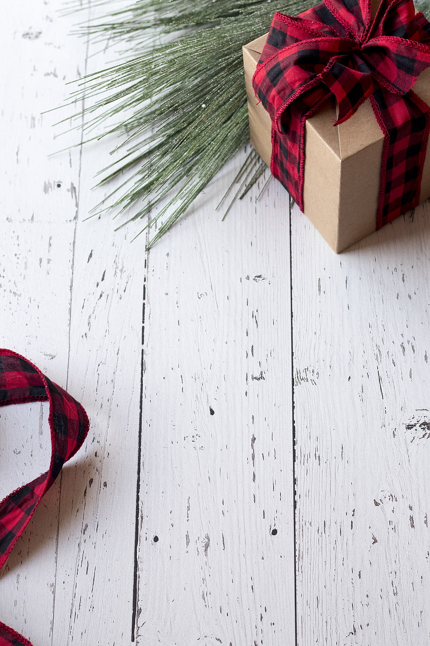Christmas gift box with plaid ribbon on white wood