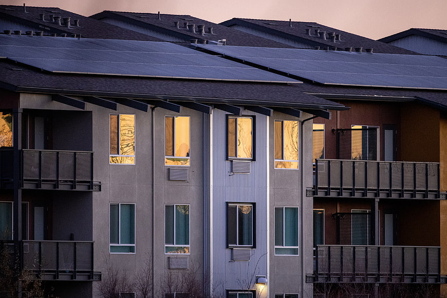 Modern Apartment Building with Solar Panels at Sunset