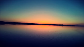 Serene Sunset Over Calm Lake With Silhouette Horizon