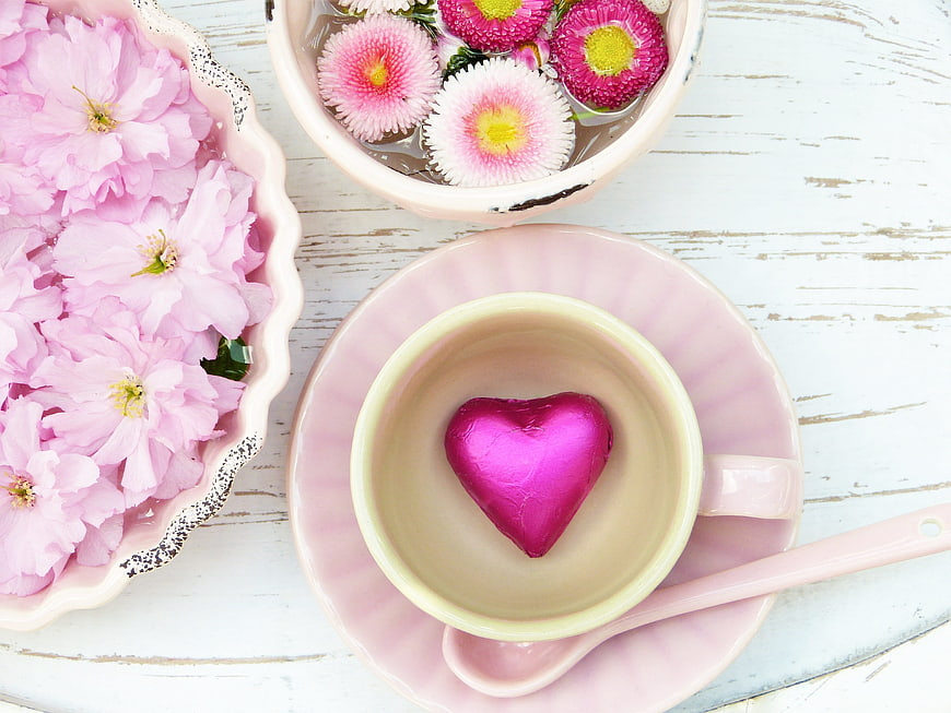 Pink heart chocolate in teacup with cherry blossoms