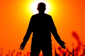 Silhouette of Man Meditating Against Vibrant Orange Sunset