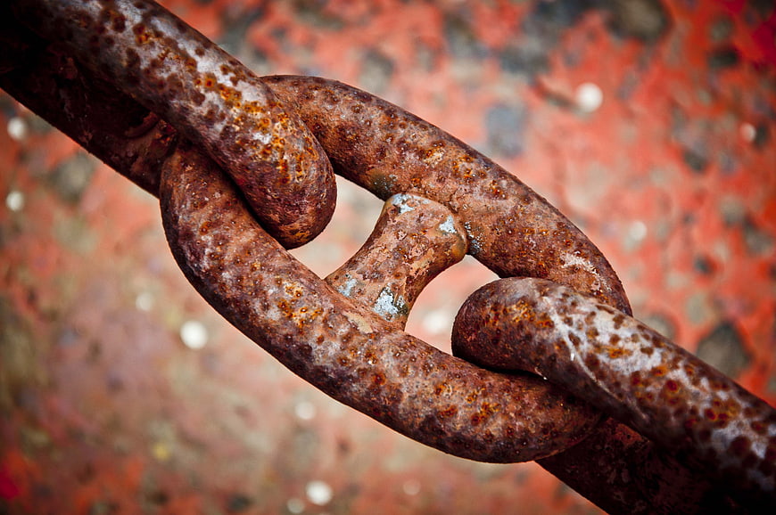 Close-up of rusty metal chain link on textured background