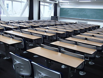 Empty university lecture hall with rows of desks and chalkboard