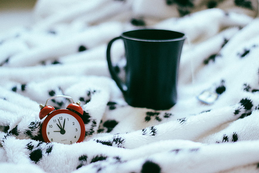 Cozy Morning Scene with Alarm Clock and Coffee Mug on Blanket
