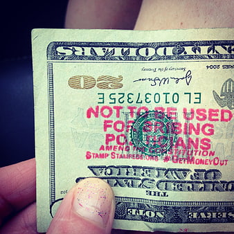 Hand holding stamped twenty dollar bill with political message