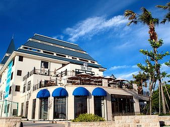 Modern white building with blue awnings and rooftop tea bar