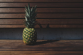 Single pineapple on wooden bench in sunlight