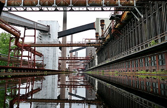 Rusty industrial factory complex with water reflection