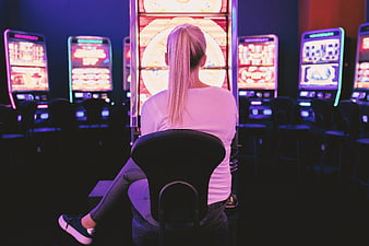 Woman Playing Slot Machine In Neon Lit Casino