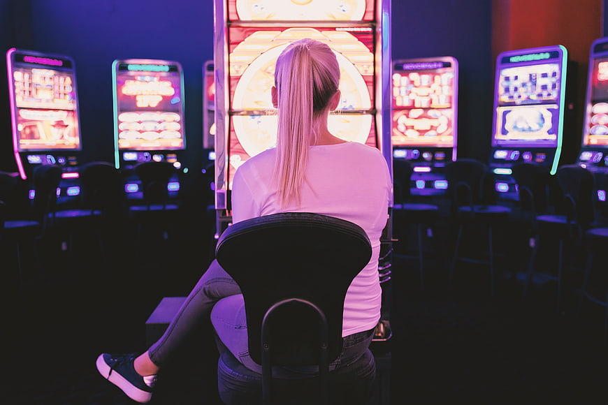 Woman Playing Slot Machine In Neon Lit Casino
