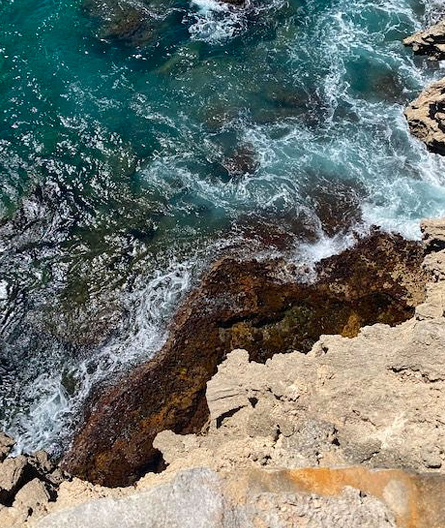 Aerial View of Turquoise Waves Crashing on Rocky Coastline