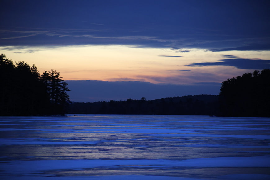 Serene Frozen Lake at Dusk with Silhouetted Forest