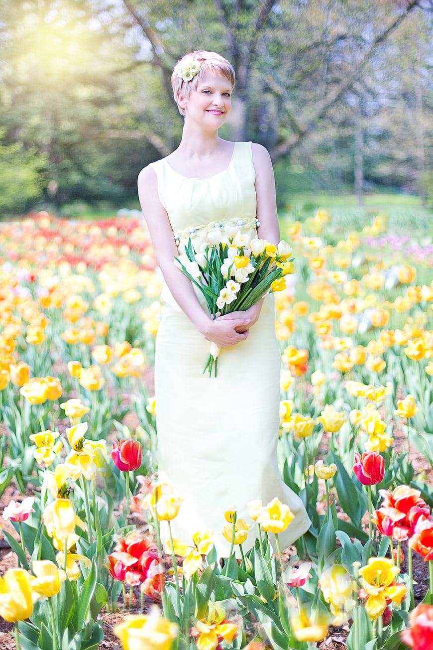 Young woman in yellow dress holding tulips in a spring flower field