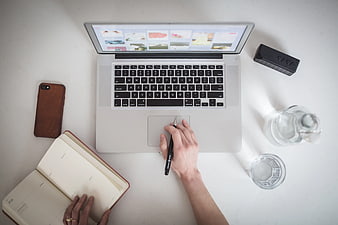 Top-down view of workspace with laptop, notebook, and water