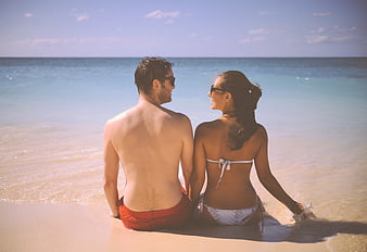 Romantic young couple sitting on a sunny tropical beach