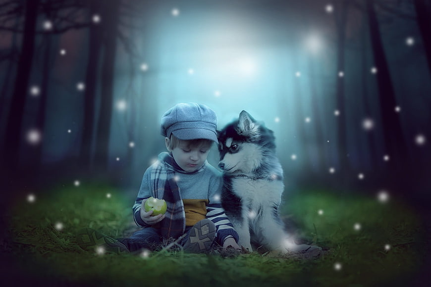 Young boy and husky puppy sitting in a magical snowy forest