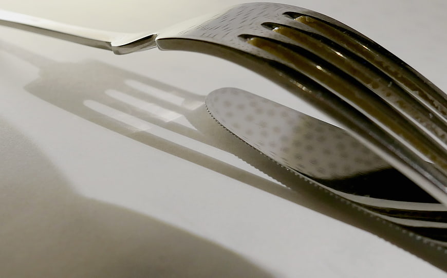 Close-up of silver fork and knife on white tablecloth